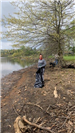 Volunteer Picking up Trash Beside the Lake