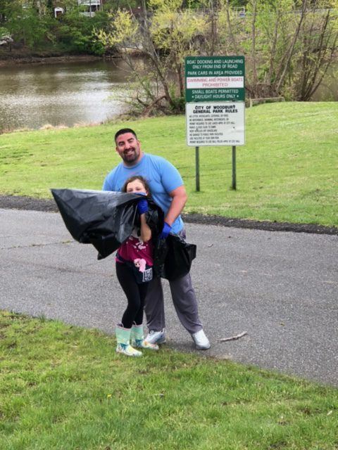 Father and Daughter Hoving a Large Bag of Trash