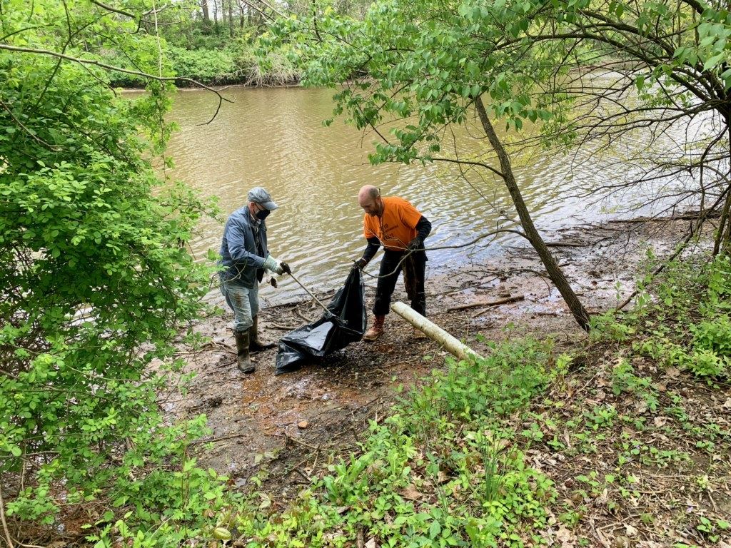 Two Men Move Trash Into a Bag